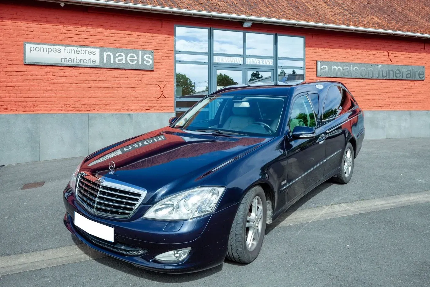 Véhicule corbillard Mercedes stationné devant l'agence des Pompes Funèbres Naels.